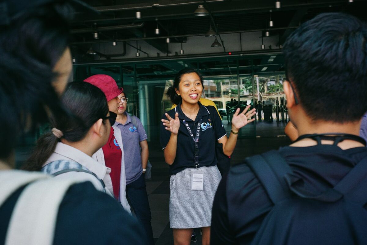 Tour guide leading a group tour, engaging visitors with gestures in an outdoor urban setting.