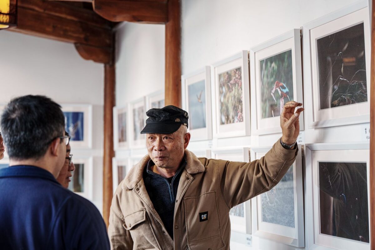 Balades Guidées Man enthusiastically explains artworks on an indoor gallery tour.